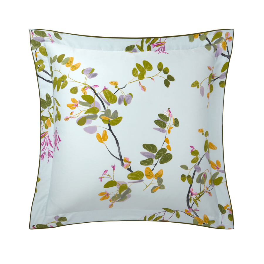 Un oreiller blanc avec des fleurs et des feuilles dessus