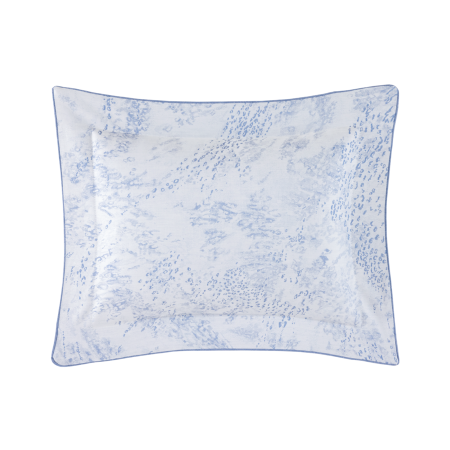 Une taie d'oreiller rectangulaire à motifs blancs et bleus, bordée d'un fin passepoil bleu.