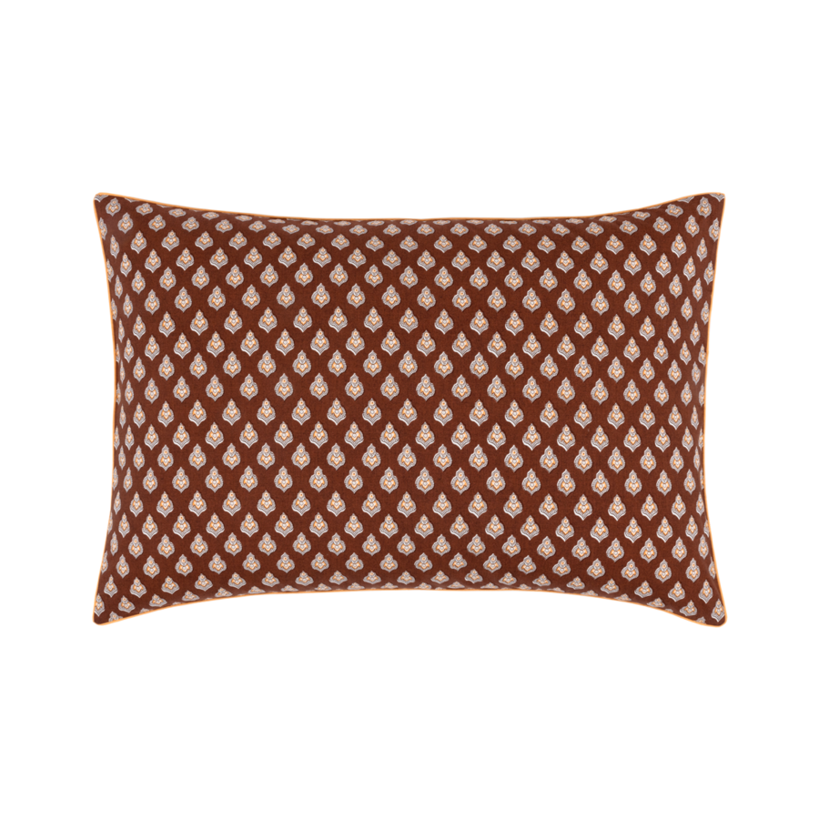 Coussin décoratif rectangulaire orné d'un motif cachemire crème répétitif sur un fond brun rougeâtre foncé.