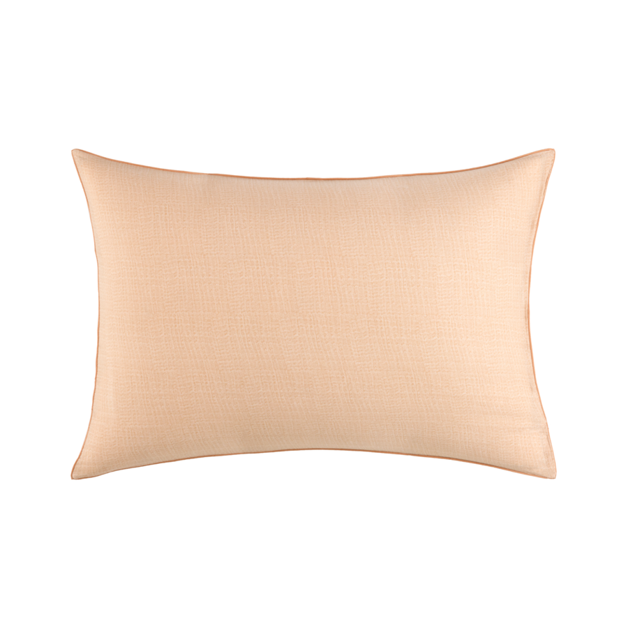 Un oreiller beige est posé sur une surface blanche.