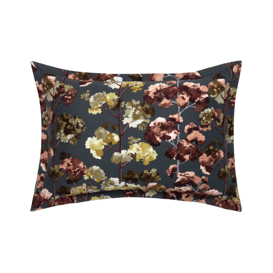 Coussin foncé à motif floral dans les tons de brun, jaune et vert sur fond gris foncé.