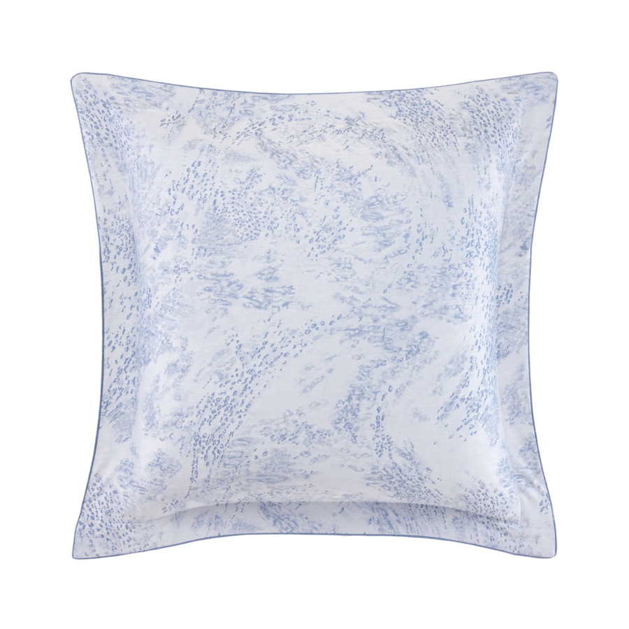 Un coussin décoratif carré à motif abstrait marbré ou pointillé bleu clair et blanc, avec un bord à volant.