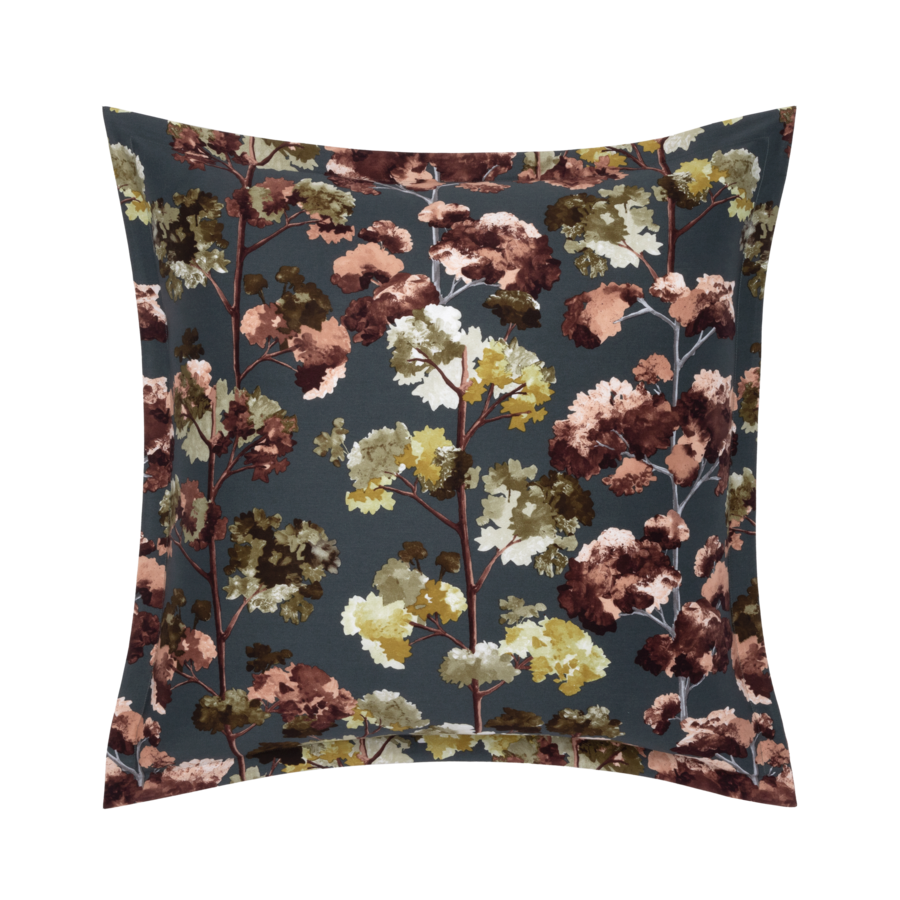 Coussin carré à motif floral dans les tons de brun, d'or et de rose sur fond gris foncé.