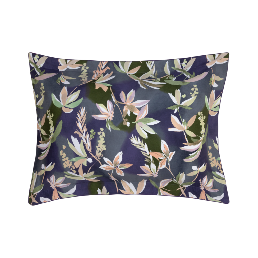 Coussin bleu à motif floral, orné de feuilles vertes, roses et blanches.