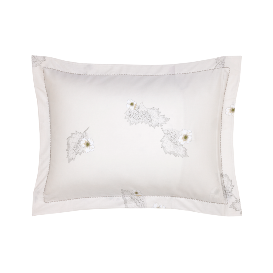 Taie d'oreiller blanche ornée de feuilles brodées et d'une bordure à motifs.