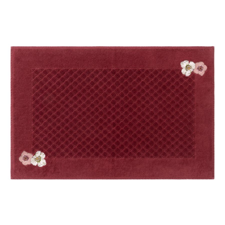 Tapis de bain bordeaux à motifs floraux.