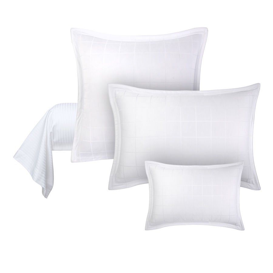 Trois oreillers blancs de différentes tailles sont placés les uns à côté des autres sur un fond blanc.