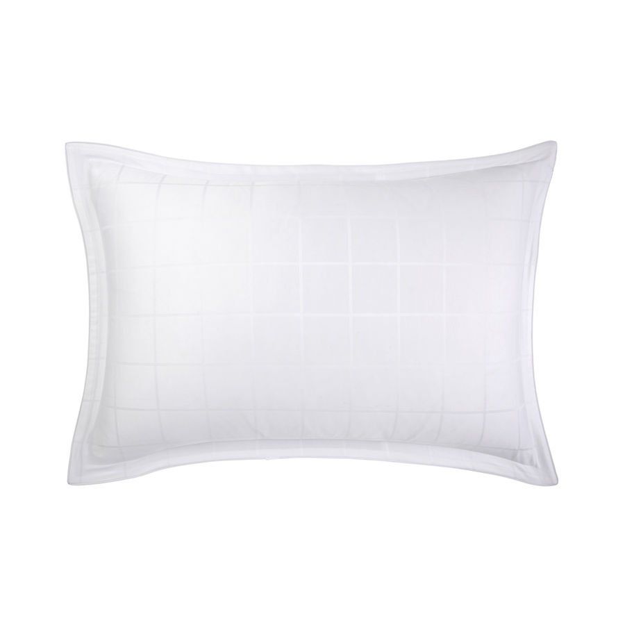 Un oreiller blanc avec un motif à carreaux dessus est sur un fond blanc.