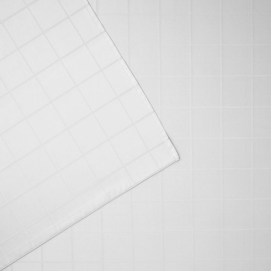 Un morceau de papier avec un motif quadrillé est posé sur une surface blanche.