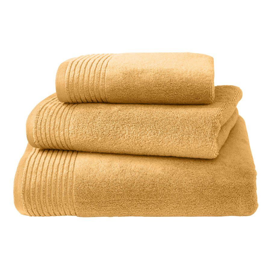 Trois serviettes jaunes sont empilées les unes sur les autres sur un fond blanc