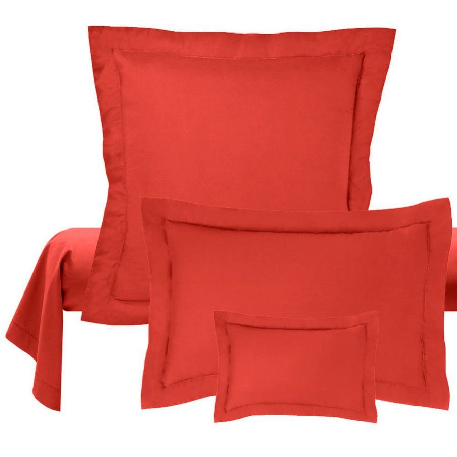 Trois oreillers rouges sont empilés les uns sur les autres sur un lit