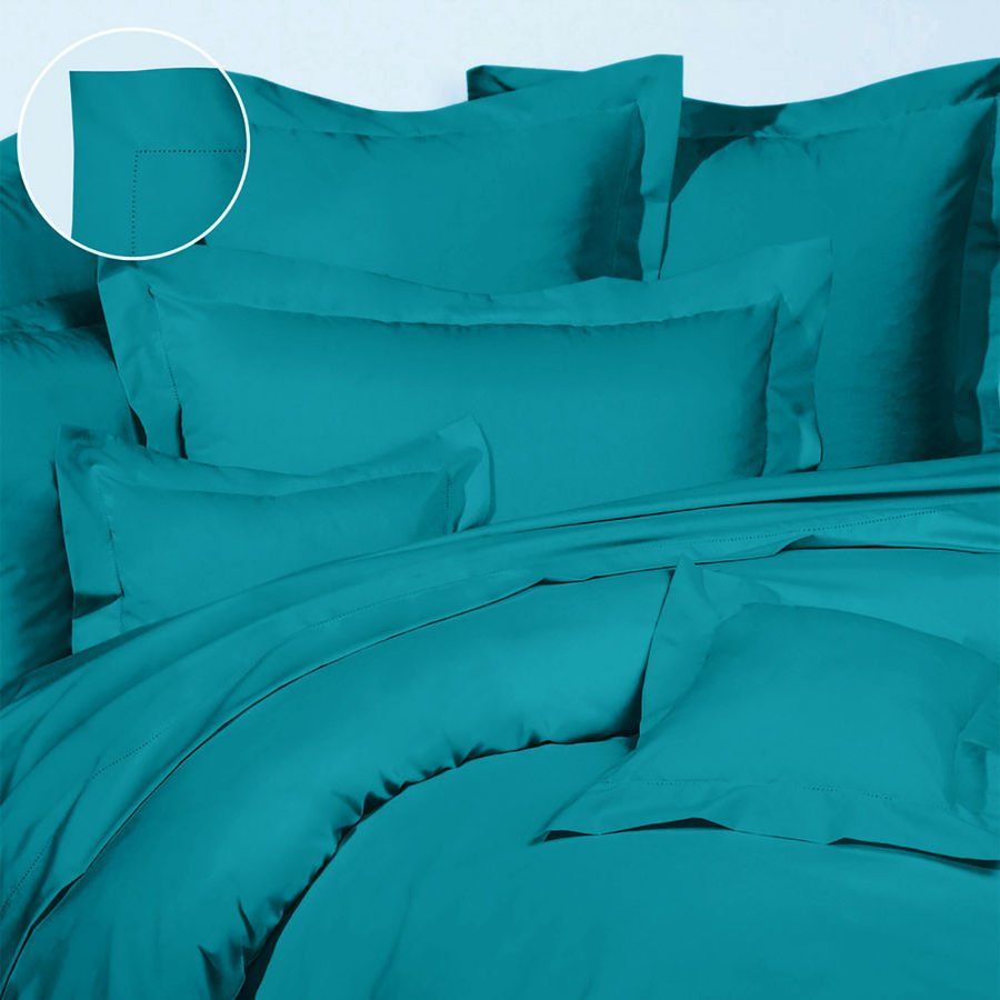 Un lit avec une couette et des oreillers turquoise