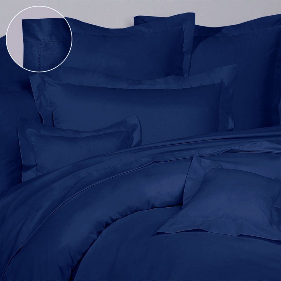 Un lit avec une couette bleue et des oreillers dessus