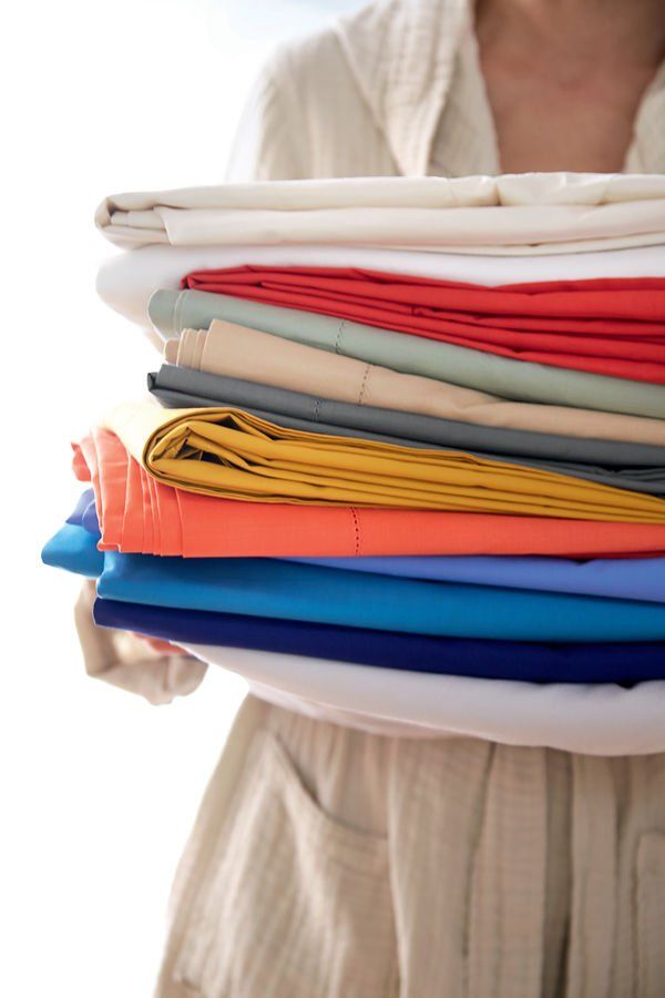 Une femme tient une pile de vêtements dans ses mains.