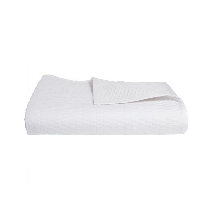 Une couverture blanche est posée sur un lit sur un fond blanc.