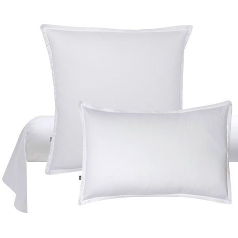 Trois oreillers blancs sont posés les uns sur les autres sur un lit.