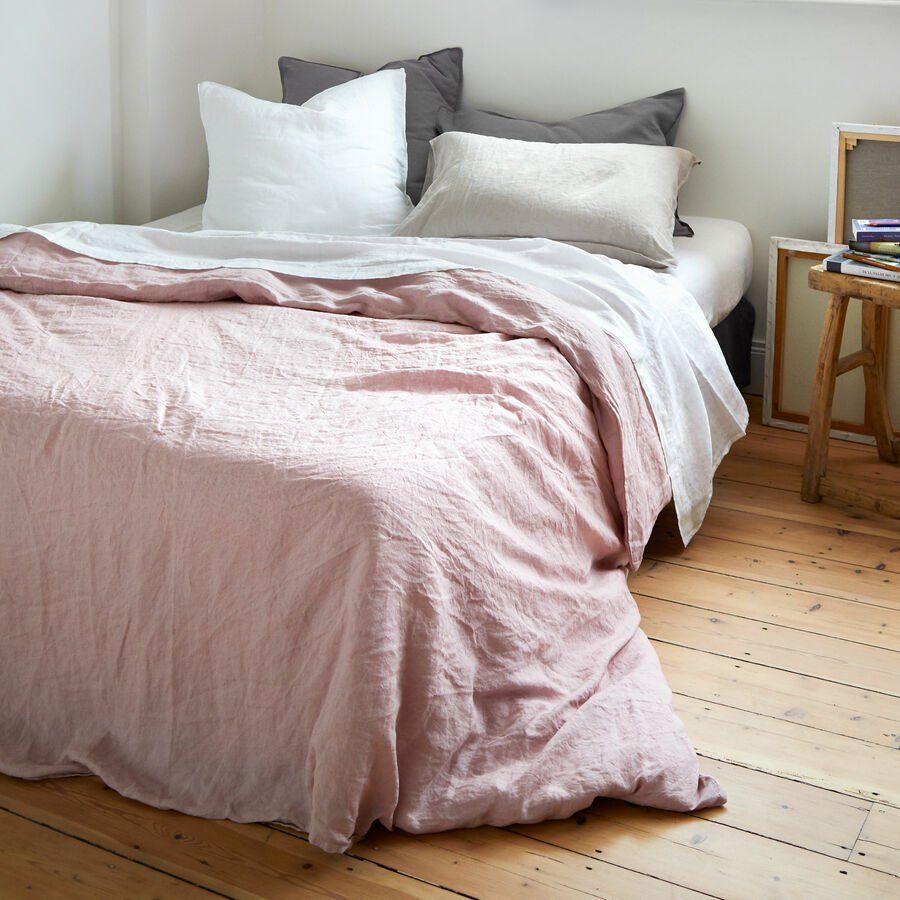 Un lit avec une couette rose et des oreillers dessus