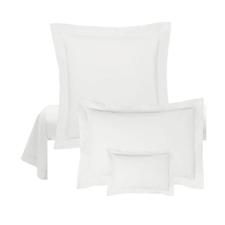 Il y a trois tailles différentes d'oreillers blancs sur un lit.