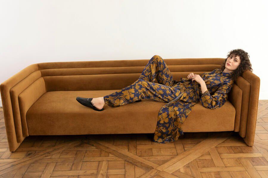 Une femme est allongée sur un canapé marron sur un plancher en bois.
