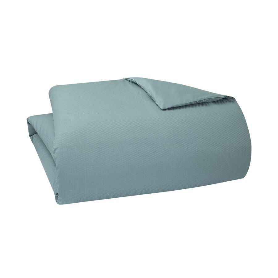 Une couette bleue est posée sur une surface blanche.