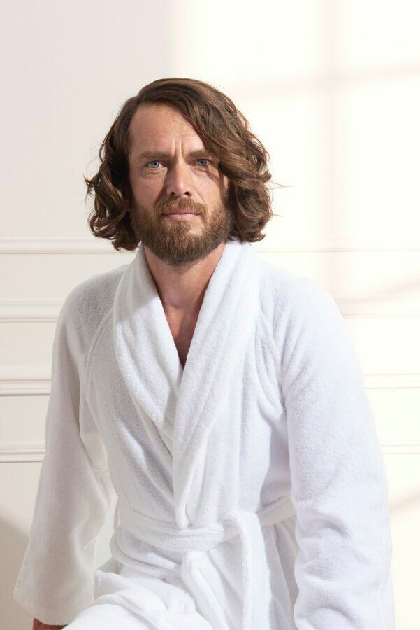 Un homme avec une barbe porte une robe blanche.