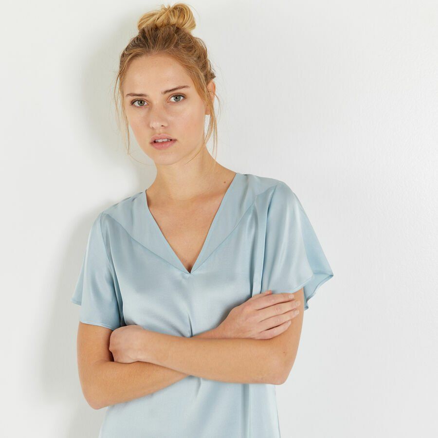 Une femme avec les bras croisés portant une chemise bleu clair