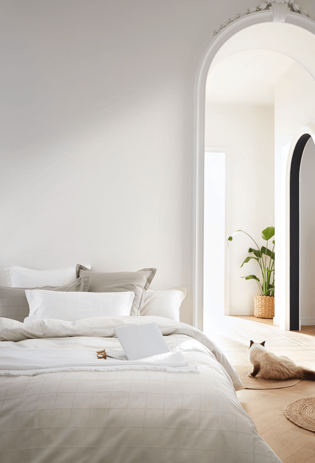 Un lit avec une couette blanche et des oreillers dans une chambre.