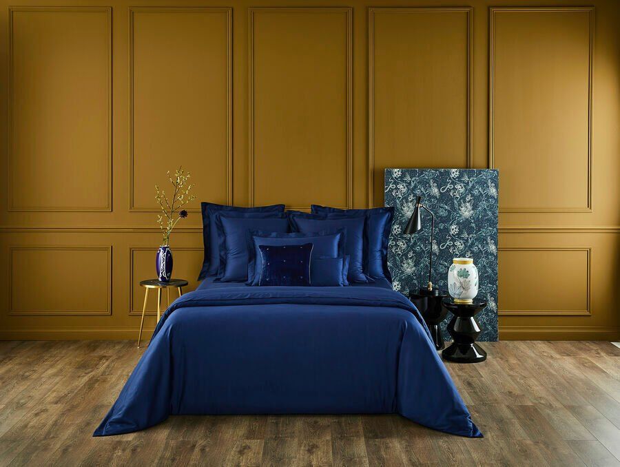 Il y a un lit avec une couette bleue et des oreillers dans la chambre.