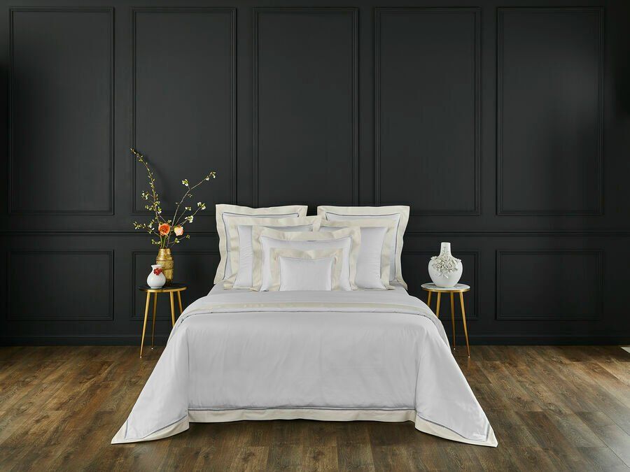 Un lit avec une couette et des oreillers blancs dans une chambre aux murs noirs.