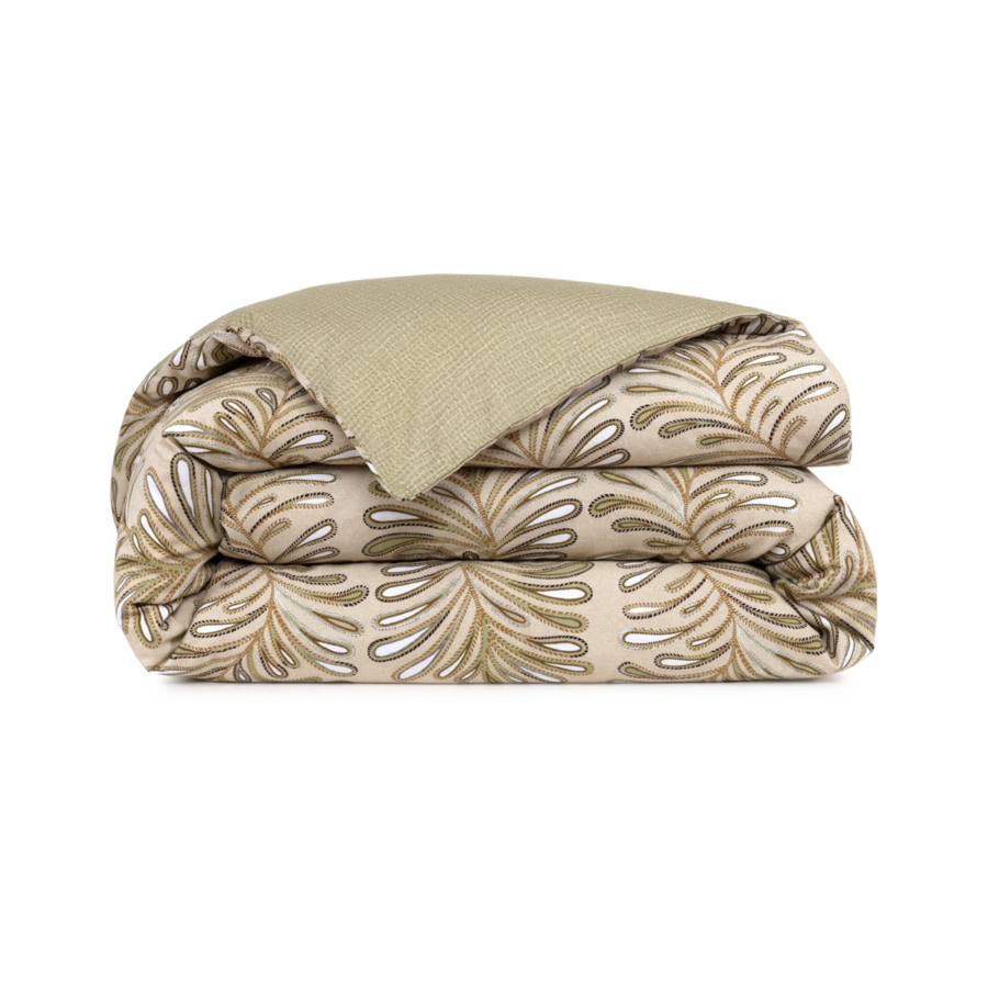 Une couette beige pliée, ornée d'un motif de feuilles tropicales métallisées or et argent, avec un dessous uni texturé olive.