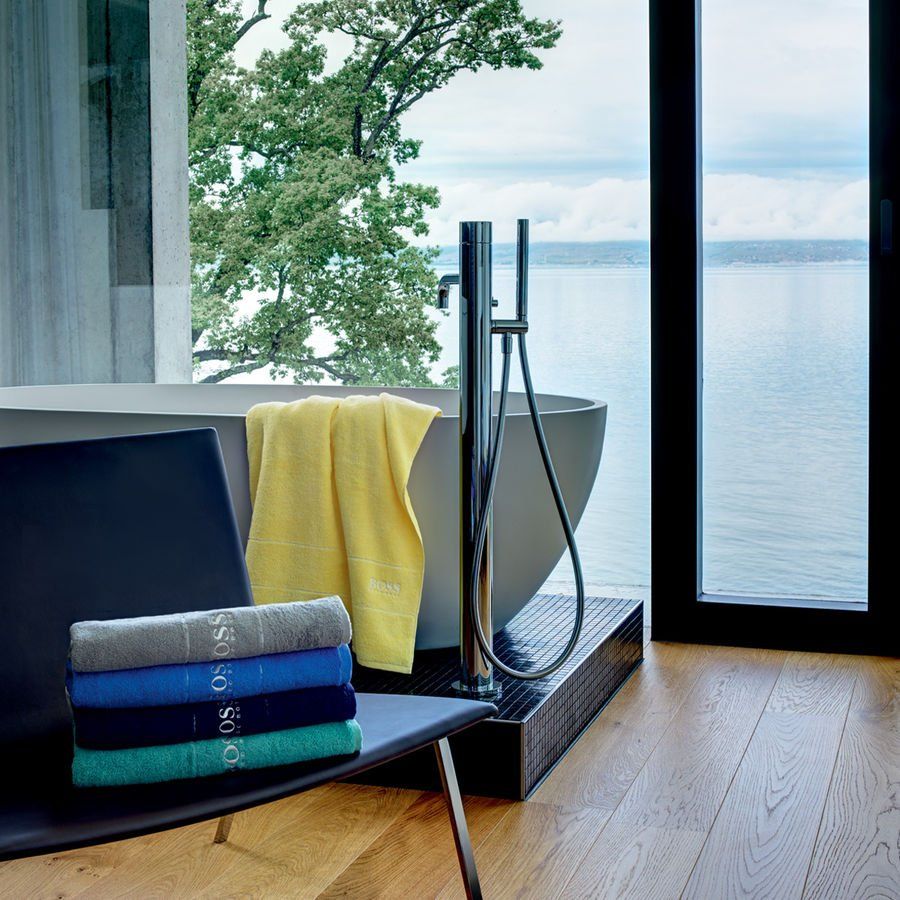 Une pile de serviettes est posée sur une chaise à côté d'une baignoire