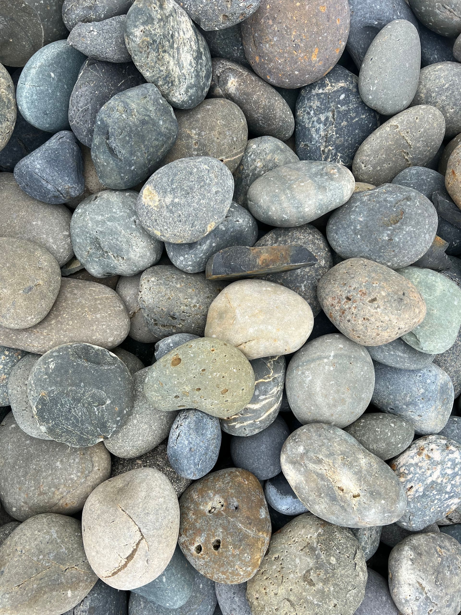 A pile of rocks of different sizes and colors are sitting on top of each other.