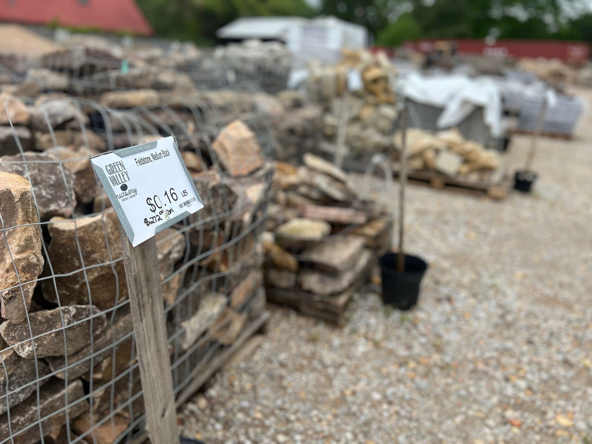 A pile of rocks behind a fence with a sign on it.
