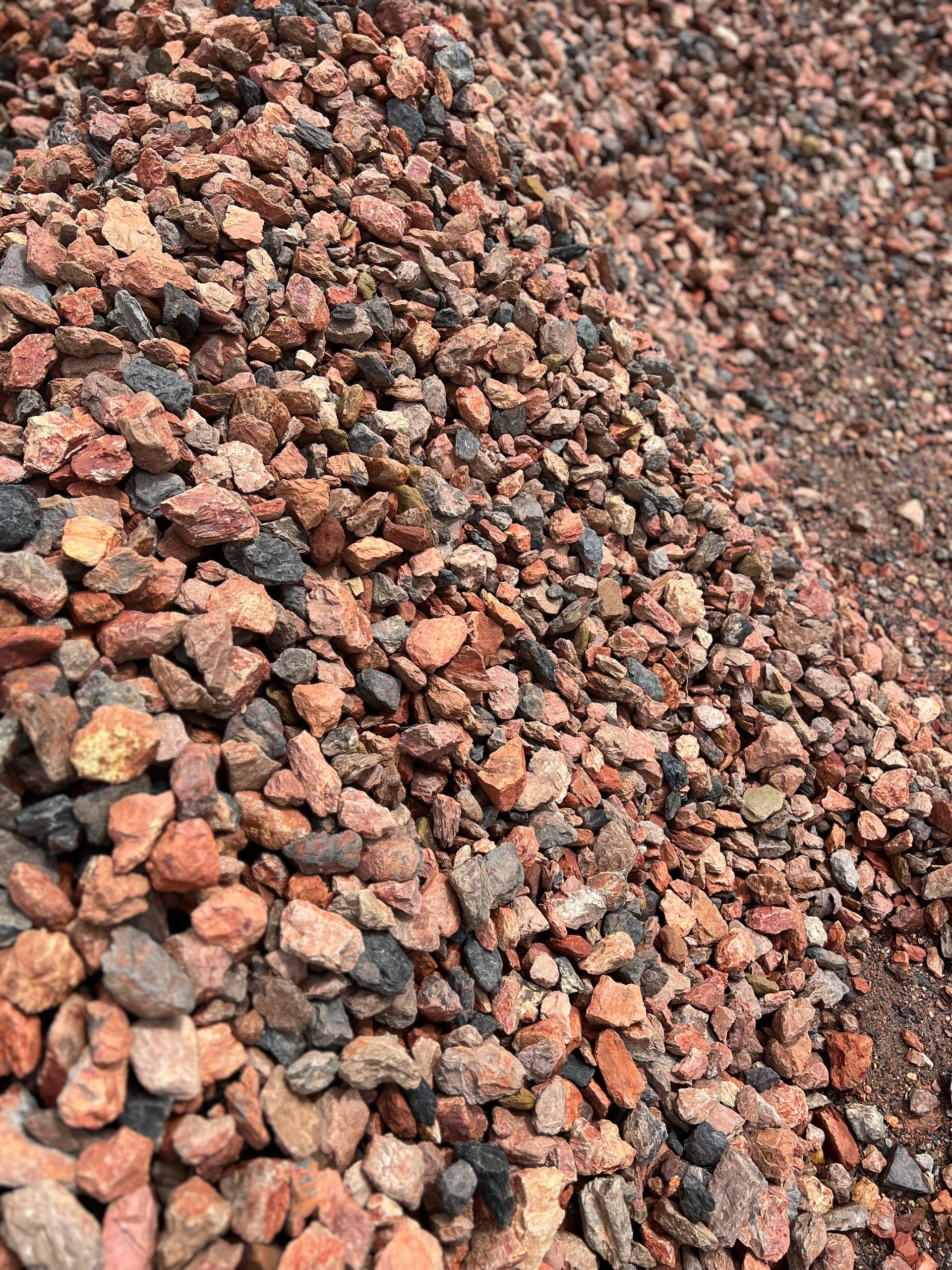 A pile of red gravel is sitting on the ground.