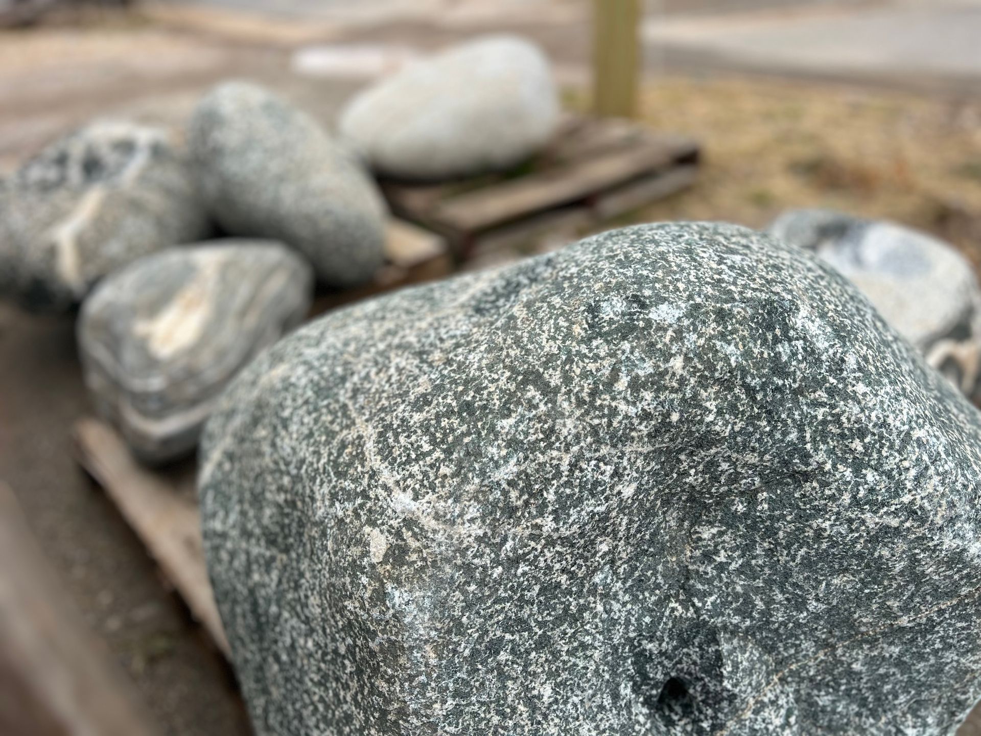 A large rock is sitting on top of a wooden table next to other rocks.