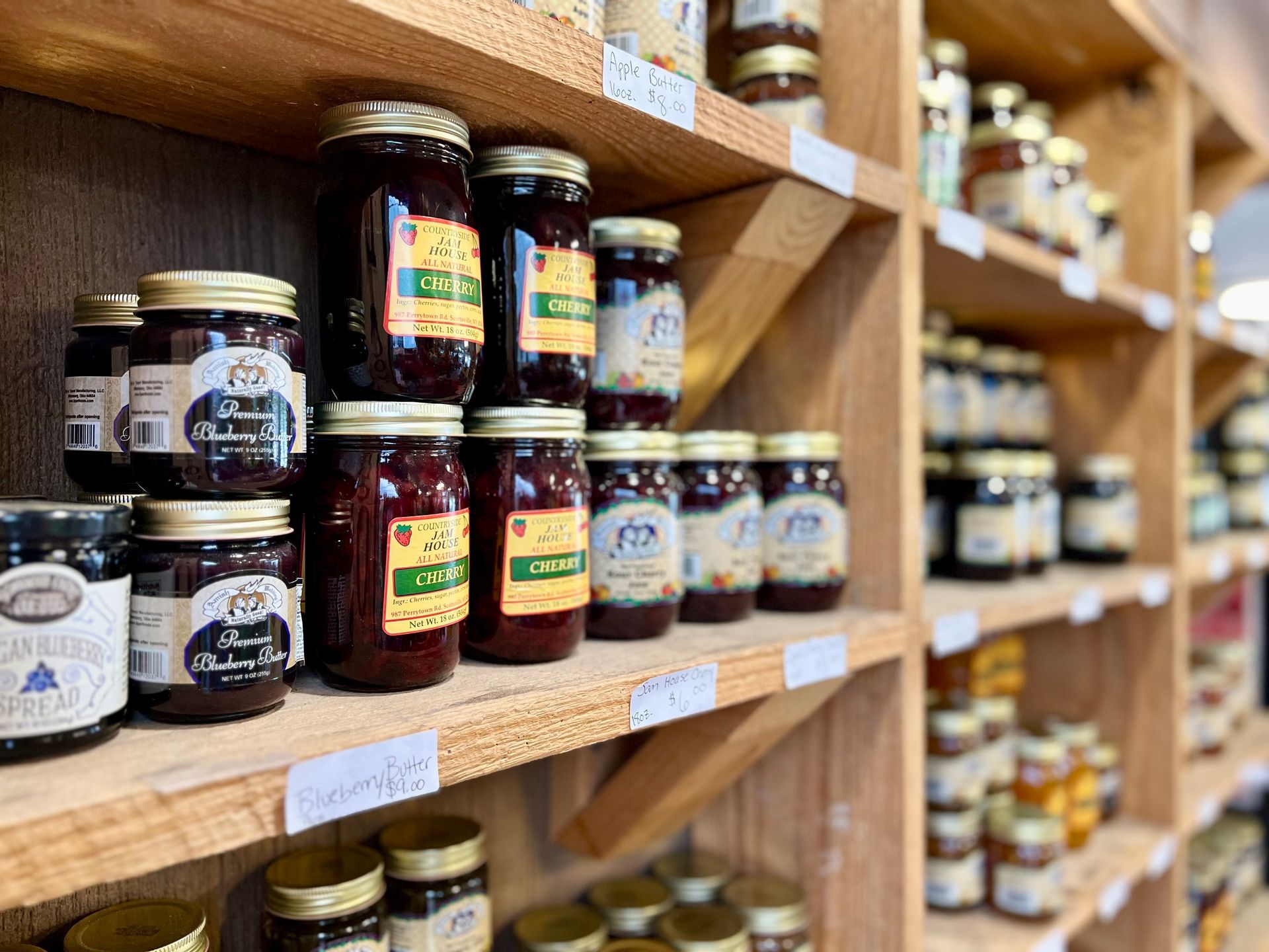 A shelf filled with jars of jam and honey in a store.