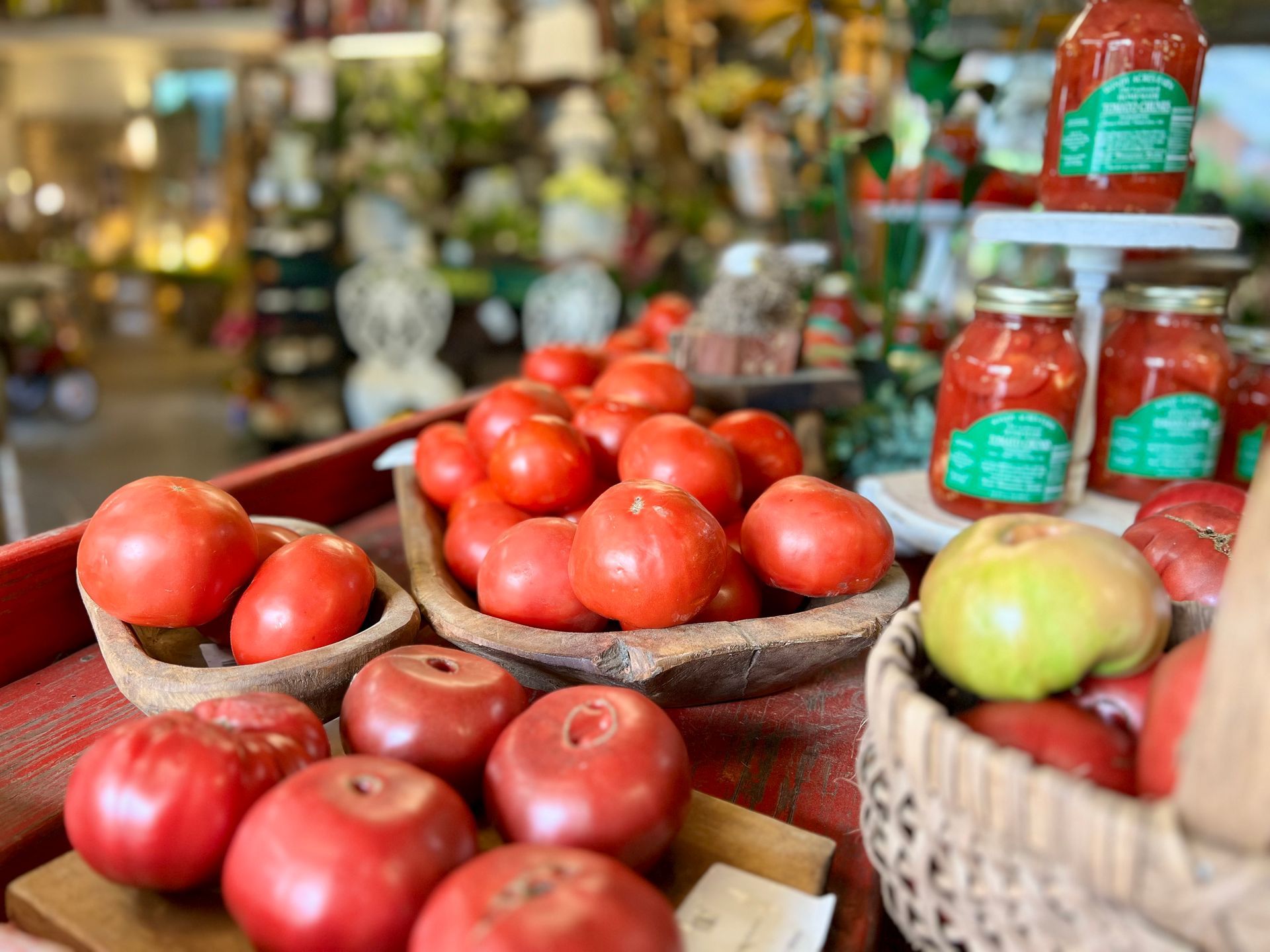 A table topped with baskets of tomatoes and apples.