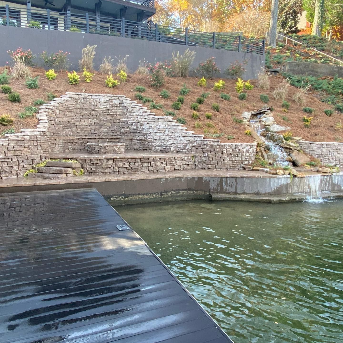 A dock next to a body of water with a waterfall in the background.
