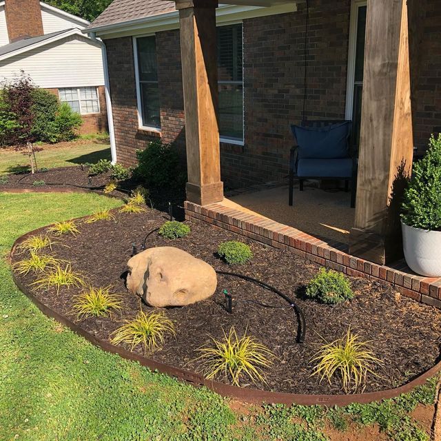 A brick house with a porch and a rock in front of it