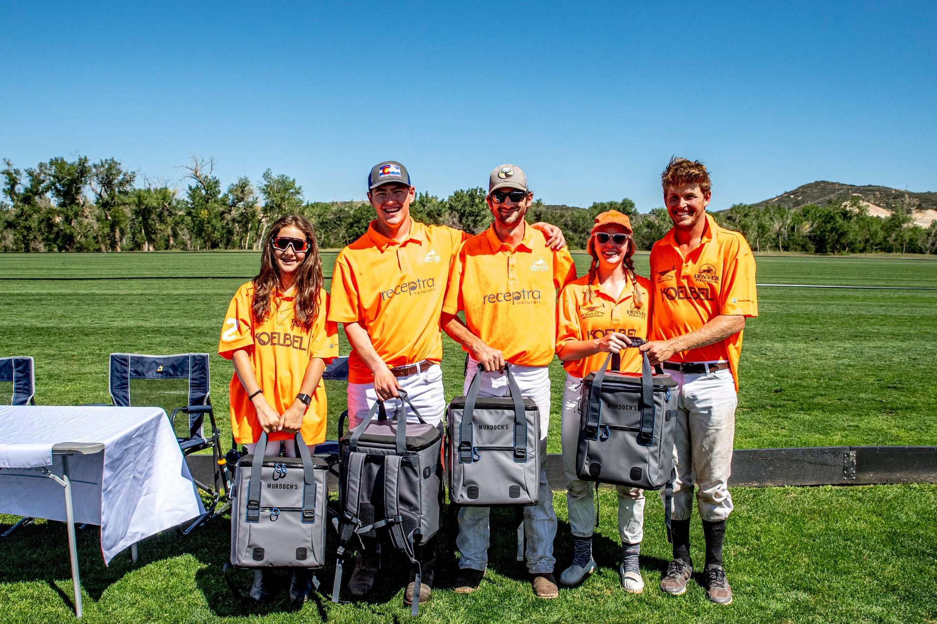 A group of people are standing in a field holding bags.