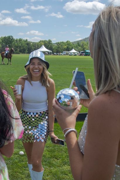 A woman taking a picture of another woman holding a disco ball