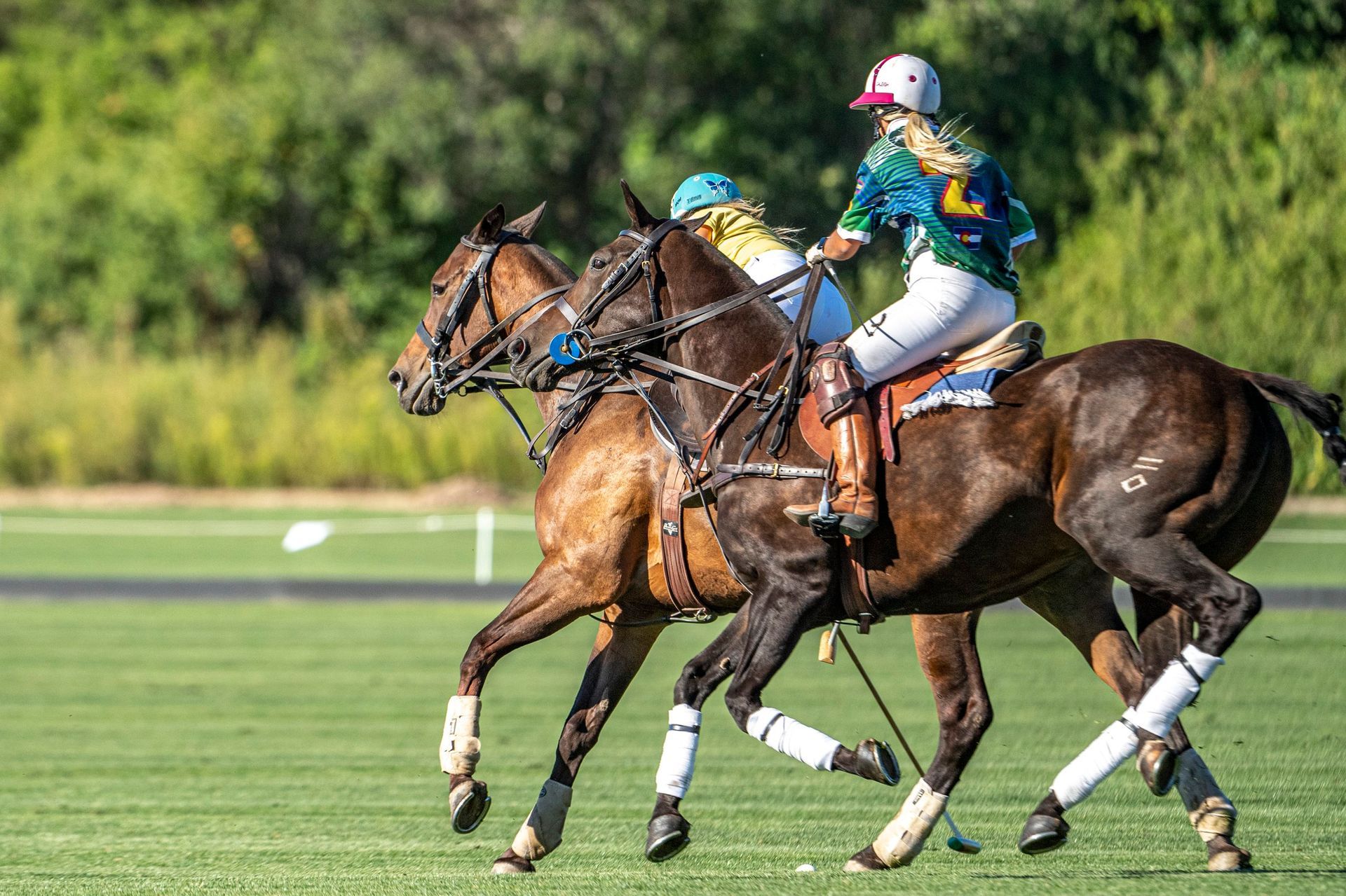 A woman is riding a horse while playing polo on a field.