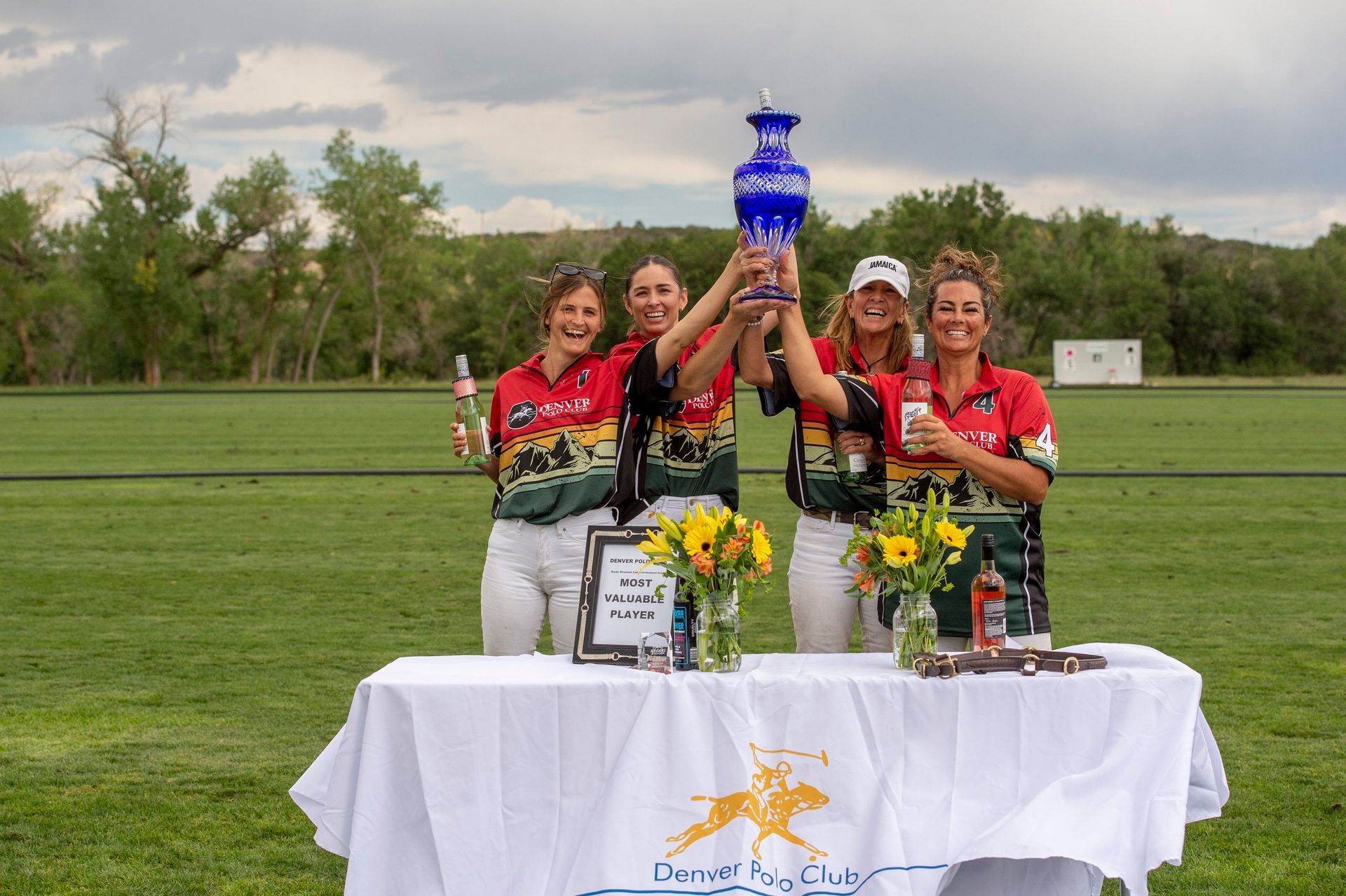 A group of women are standing around a table holding a trophy.