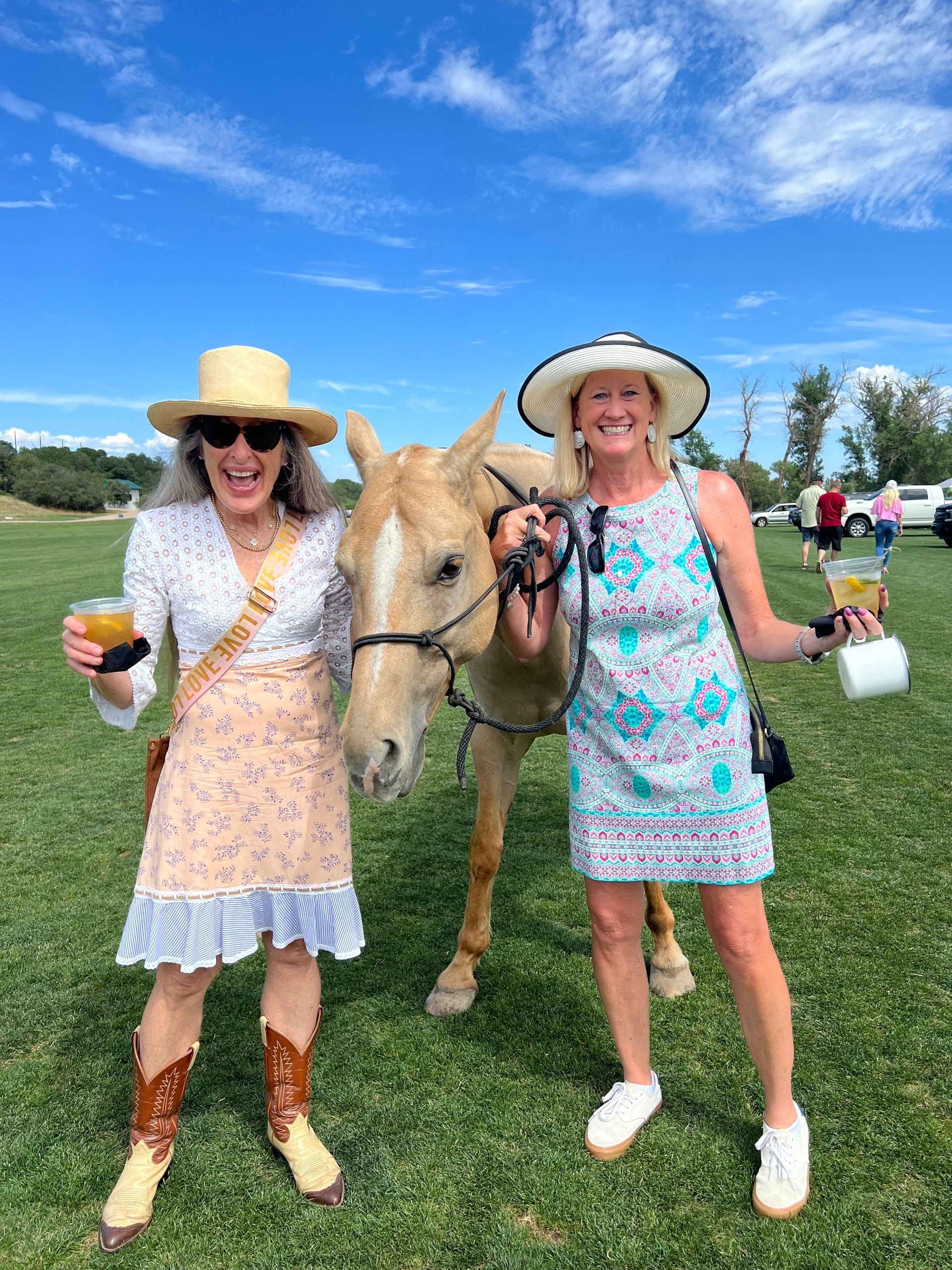 Two women are standing next to a horse in a field.
