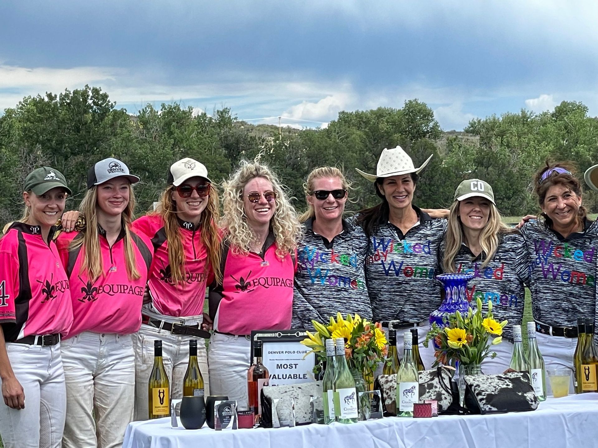 A group of women are posing for a picture in front of a table.
