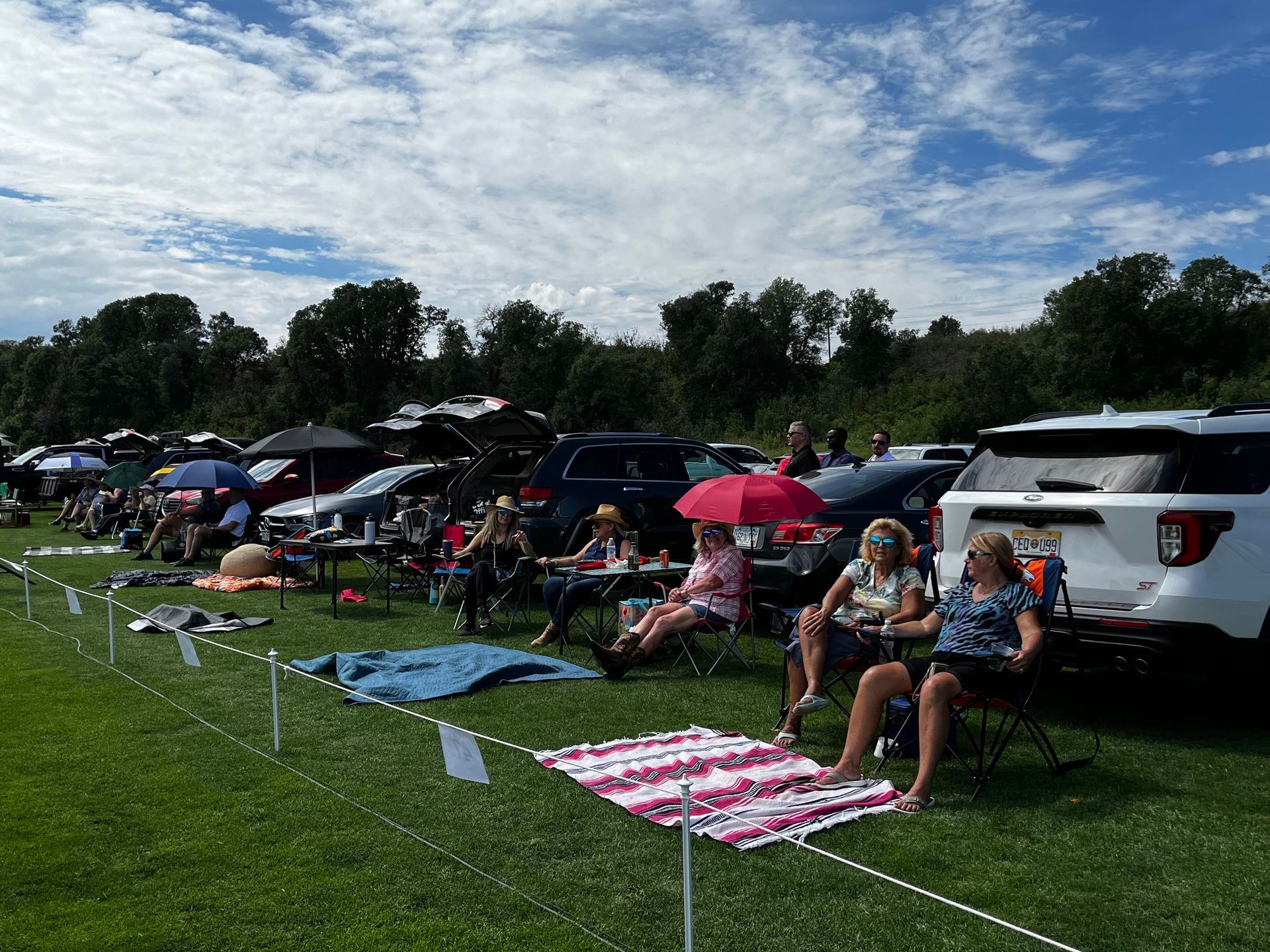 A group of people are sitting in chairs in a grassy field.