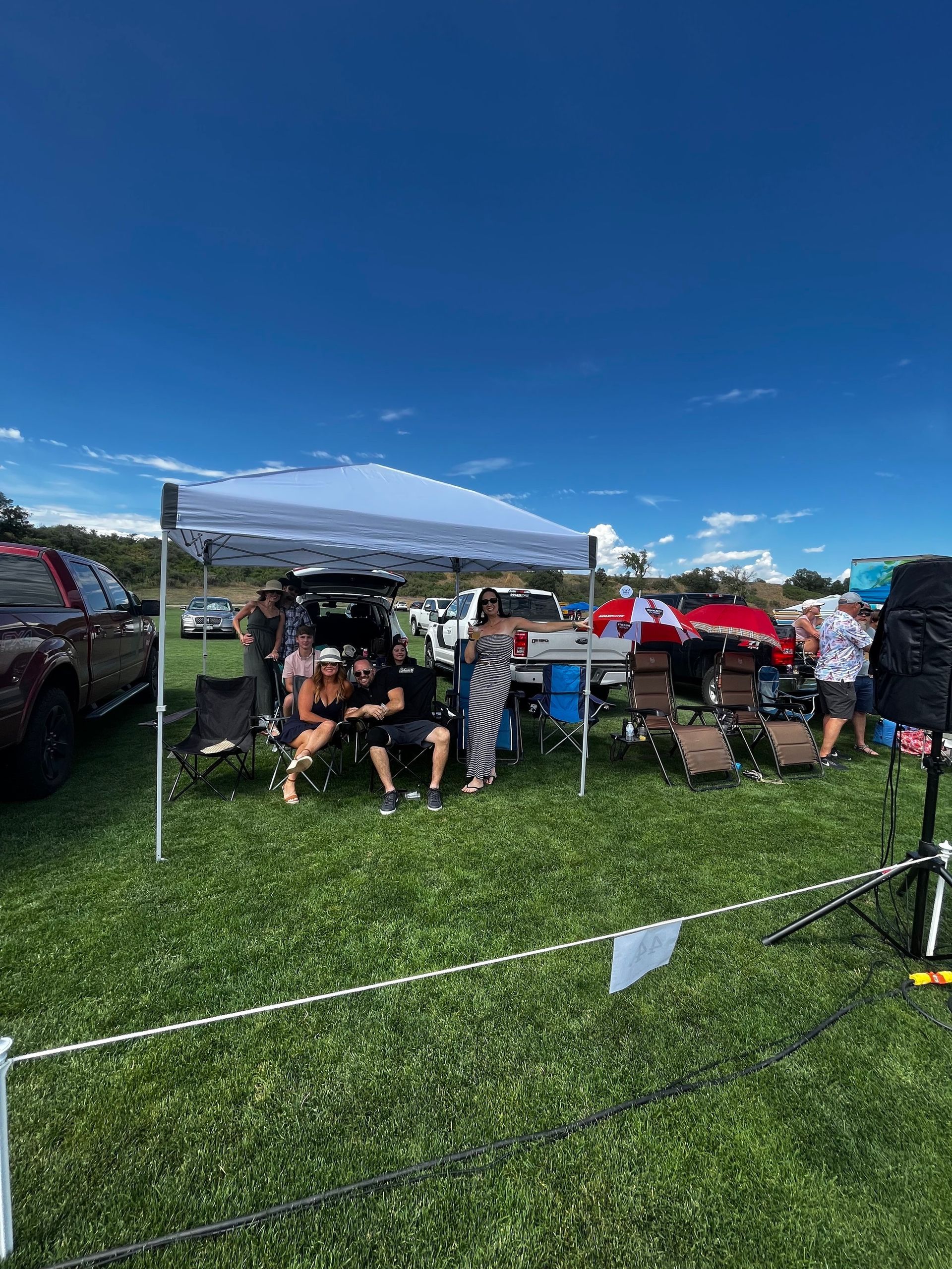 A group of people are sitting under a tent in a field.