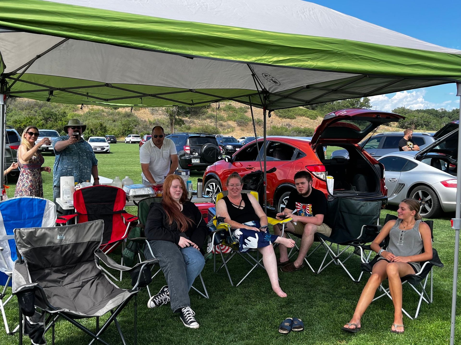 A group of people are sitting under a tent in a field.