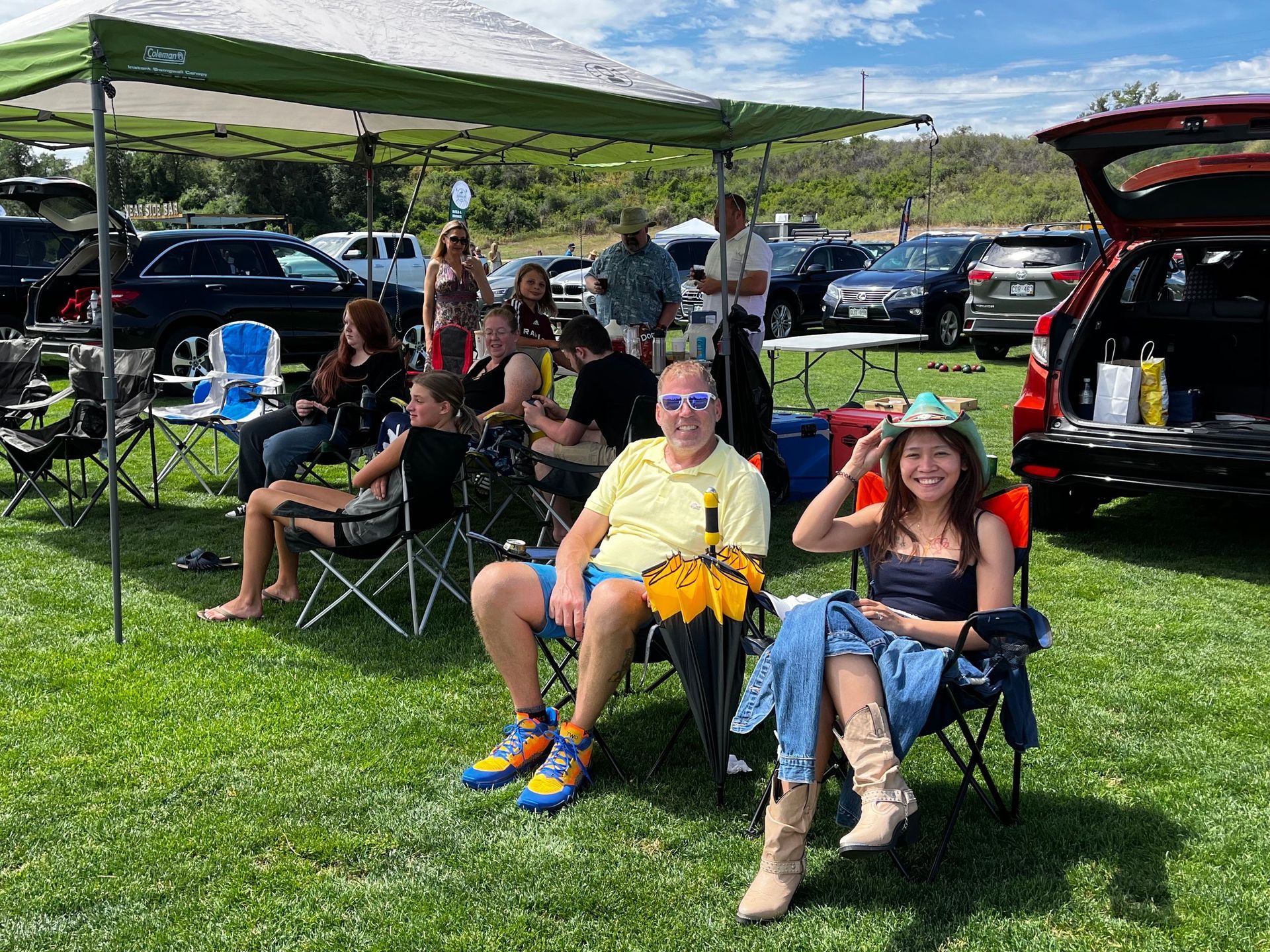 A group of people are sitting in chairs under a tent in a field.