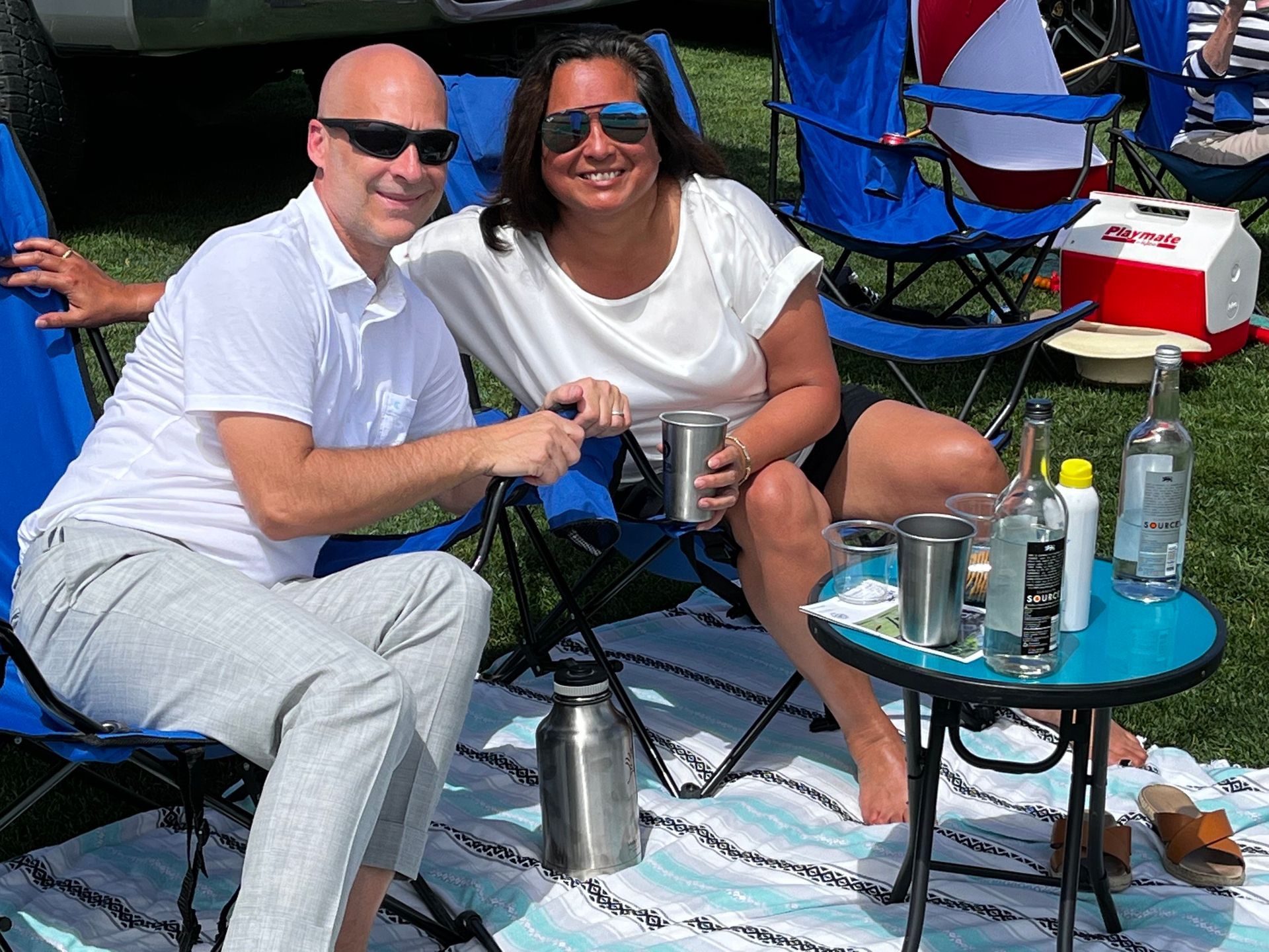 A man and a woman are posing for a picture while sitting on a blanket.
